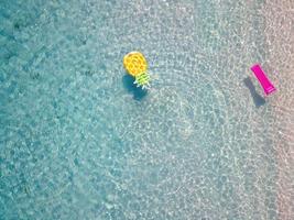 Drone aerial view of inflatable pineapple on exotic tropical pink beach
