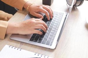 Hand of businessman or worker typing on a laptop keyboard with empty book and classic alarm clock photo