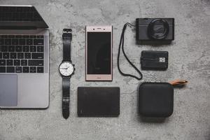 Flat lay top view of work concept with computer laptop and travel accessories on grey concrete wall photo