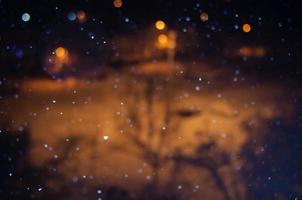 Nighttime falling snow with a bokeh effect against a background of city lights. photo