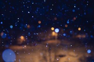 Nighttime falling snow with a bokeh effect against a background of city lights. photo