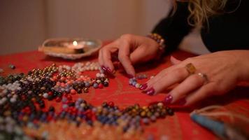 vrouwenhanden werken met koralen om koraalarmbanden op tafel te maken video