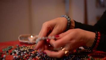 as mãos das mulheres trabalham com corais para fazer pulseiras de coral em uma mesa