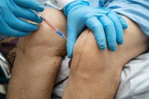 Asian doctor inject Hyaluronic acid platelet rich plasma into the knee of senior woman to walk without pain. photo