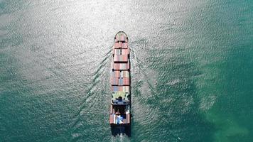 Aerial top view stern of smart cargo ship carrying container and running very fast for export cargo from container yard port to custom ,Contrail line in the ocean by large ship very fast.