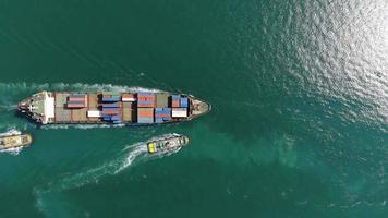 vista aérea do navio porta-contentores de carga por rebocador para o conceito de porto de terminal internacional transporte de mercadorias por navio video