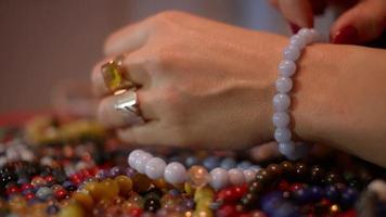 Women's hands works with Corals to make a Coral Bracelets on a Table video