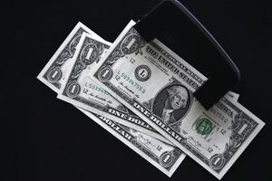 billetes de dólar en un fondo negro y un perforador foto