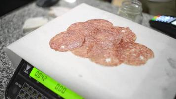 Der Verkäufer im Lebensmittelgeschäft legt geschnittene Salami auf die elektronische Waage video