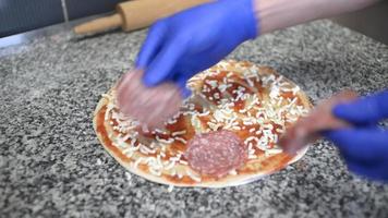 en kock förbereder en pizza med tomat, mozzarella och salami video