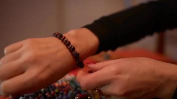 les mains des femmes travaillent avec des coraux pour fabriquer des bracelets de corail sur une table video