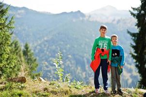 Brothers hike in the mountains, children are walking along a mountain trail, outdoor activities with children, sibling, boy with his brother traveling. photo