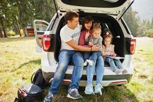 Family with two baby girls at vehicle interior. Children in trunk. Traveling by car in the mountains, atmosphere concept. photo