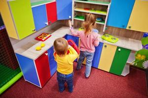 lindas hermanas jugando en el centro de juegos interior. sala de juegos de jardín de infantes o preescolar. en la cocina de los niños.