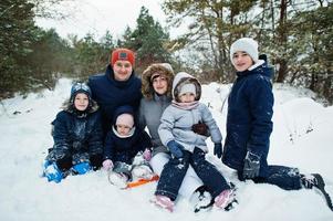 padre y madre con cuatro hijos en la naturaleza invernal. al aire libre en la nieve. foto