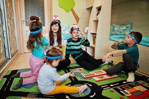 familia feliz con cuatro niños jugando adivina quién mientras se divierte en casa. foto