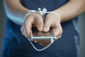 Hands tied with earphone wire. In the hands of the phone. The concept of dependence on gadgets. photo