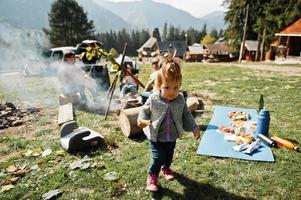 Family bonfire in mountain. Mother with four kids camping. Autumn hike and camp weather. Warming and cooking near flame together. photo