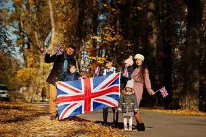 National holiday of United Kingdom. Large family with four kids holding british flags in autumn park.  Britishness celebrating UK. photo