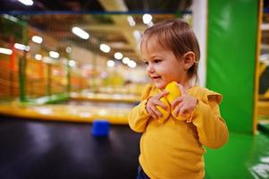 linda niña jugando en el centro de juegos interior. sala de juegos de jardín de infantes o preescolar. sosteniendo limones de plástico en las manos.