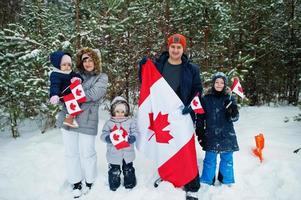 Family holding flag of Canada on winter landscape. photo