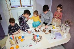 Mother with four kids makes a wreath for Christmas Eve and crafting decorating. New Year celebration. photo