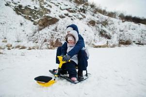 Brother and sister enjoy a sleigh ride. Child sledding. Kid riding a sledge on winter. photo