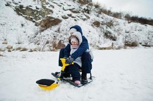 hermano y hermana disfrutan de un paseo en trineo. trineo infantil. niño montando un trineo en invierno. foto