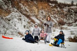 Family plays and sleigh rides in winter outdoor, mother and children having fun. photo