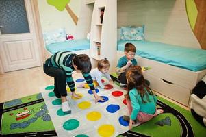 Happy family having fun together,four kids playing twister game at home. photo