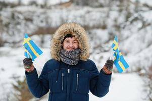 Scandinavian man with Sweden flag in winter swedish landscape. photo