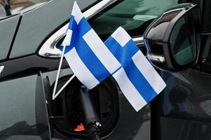 concepto de coche ecológico de bandera finlandesa. conectar un proveedor de energía, cargar un automóvil moderno. foto