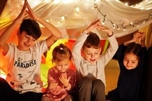 Playing kids in tent at night home. Hygge mood. photo