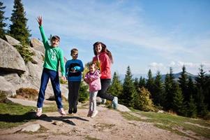 Mother with four kids resting in mountains. Family travel and hiking with childrens. Jumping into the air. photo