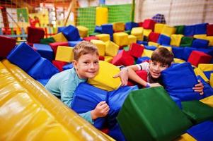 dos hermanos tirados en la piscina con cubos de espuma de colores en el centro de juegos interior. foto