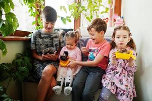 Four children holding their favorite pets on hands. Kids playing with hamster,turtle at home. photo