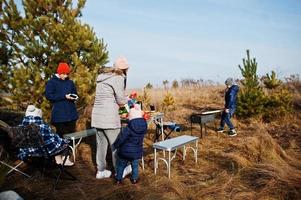 Family barbecuing on a deck in the pine forest. Bbq day with grill. photo