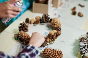 las manos de la madre y los niños hacen una corona para la víspera de Navidad y la decoración artesanal. celebración de Año Nuevo. foto