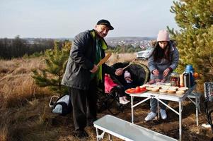 Family barbecuing on a deck in the pine forest. Cooking outdoors. photo