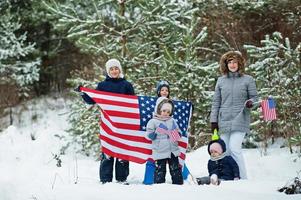 familia con cuatro hijos sosteniendo la bandera de estados unidos en el paisaje invernal. foto