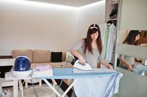 la joven está planchando ropa en casa. foto