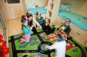 familia feliz con cuatro niños jugando adivina quién mientras se divierte en casa. foto