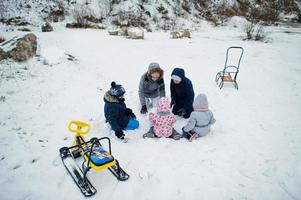 Family plays and sleigh rides in winter outdoor, mother and children having fun. photo