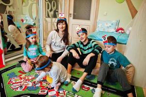 familia feliz con cuatro niños jugando adivina quién mientras se divierte en casa. foto