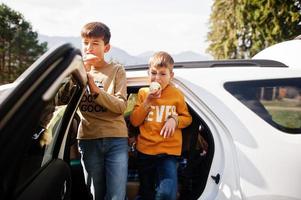 Two brothers eat apples at vehicle interior. Traveling by car in the mountains, atmosphere concept. photo