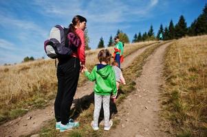 Woman is traveling with a childrens. Mom in the mountains. Climb to the top of the mountain with children. With the backpack climbed to the top. photo