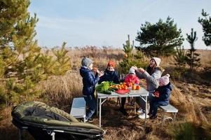 Cheerful mother with kids at a picnic. Family on vacation with fruits outdoor. photo