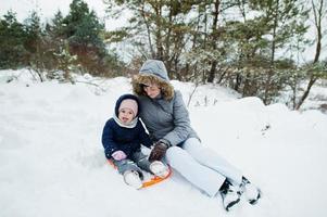 Mother with baby girl daughter in winter nature. Outdoors in snow.