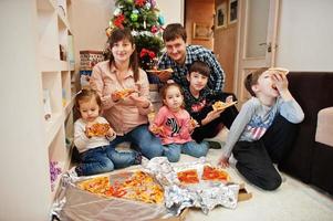 familia feliz con cuatro hijos comiendo pizza en casa. foto