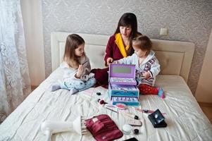 Mother and daughters doing makeup on the bed in the bedroom. photo